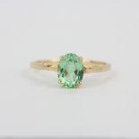 A hallmarked 9ct yellow gold (marked 10K) solitaire ring set with an oval cut peridot, (O).