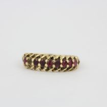 A hallmarked 9ct yellow gold ring set with round cut rubies, (O). One ruby missing.