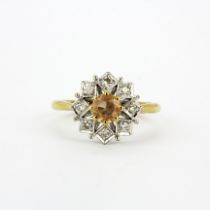 A hallmarked 18ct yellow and white gold ring set with an imperial topaz surrounded by diamonds, (