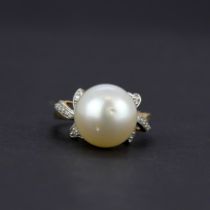 A 10ct yellow gold (marked 10K) ring set with a large cultured pearl and diamond shoulders, (O).