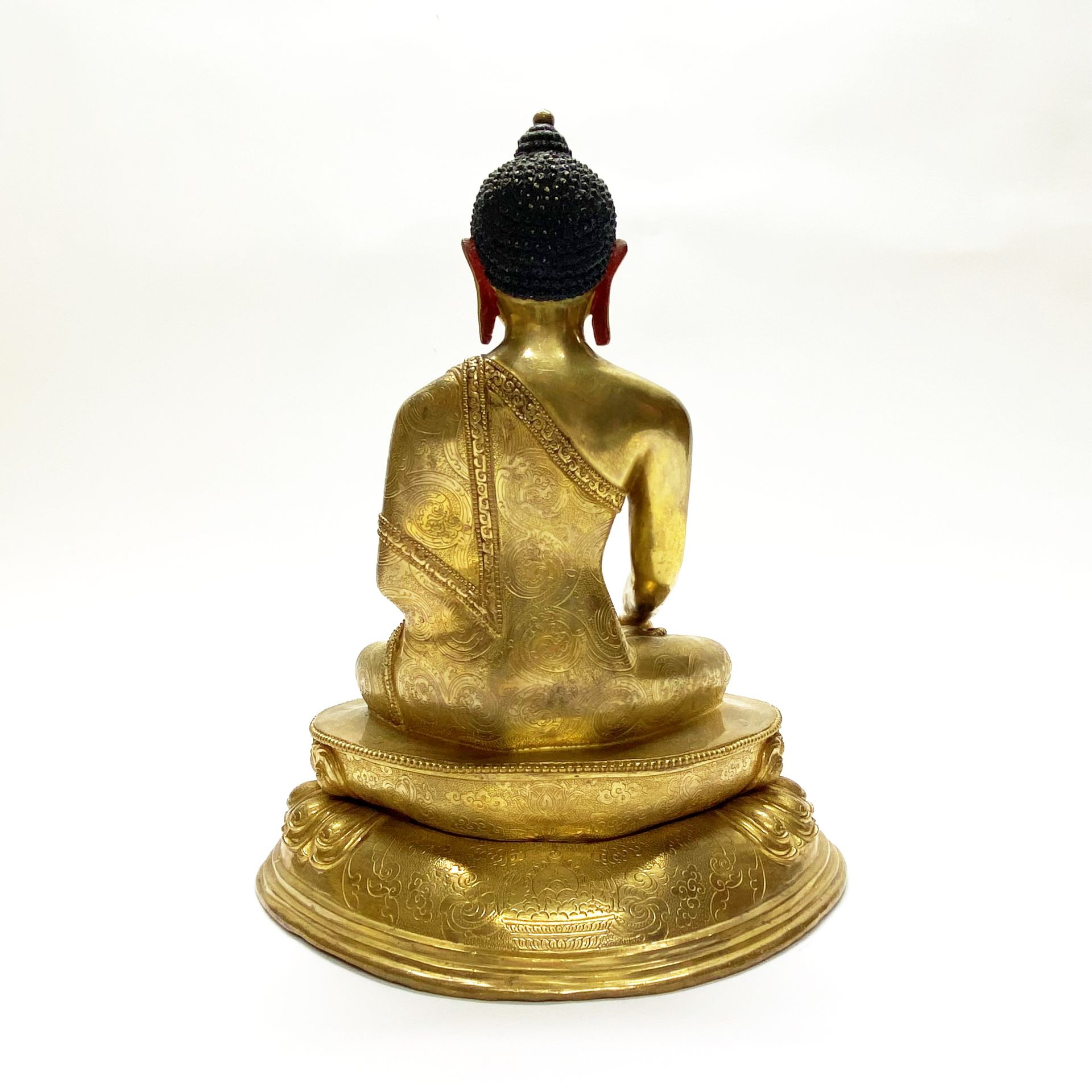 A Tibetan gilt bronze figure of seated Buddha with hand painted temple quality face. H. 30cm - Image 2 of 2
