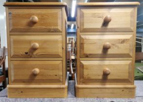 A pair of pine three drawer bedside tables, 64 x 42 x 42cm.