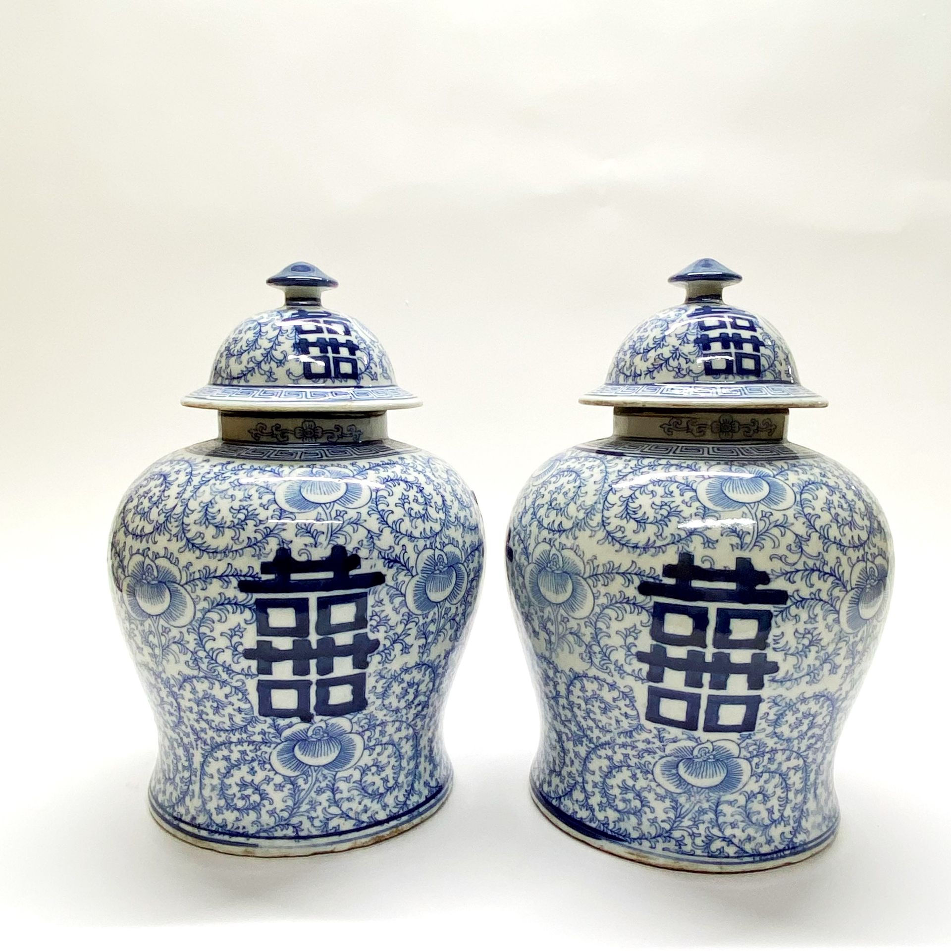 A pair of Chinese hand painted porcelain jars and lids featuring the character for double