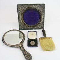 A hallmarked silver photo frame with a matching hand mirror, silver handled brush and a cased silver