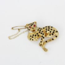 A 9ct yellow gold leopard brooch set with sapphires, diamonds and ruby eyes, L. 3.7cm.