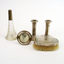 A pair of hallmarked silver candlesticks, a circular silver photo frame, silver backed brush and a