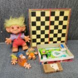 A boxed clockwork tin toy with a group of trolls and a draughts set.