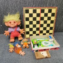 A boxed clockwork tin toy with a group of trolls and a draughts set.