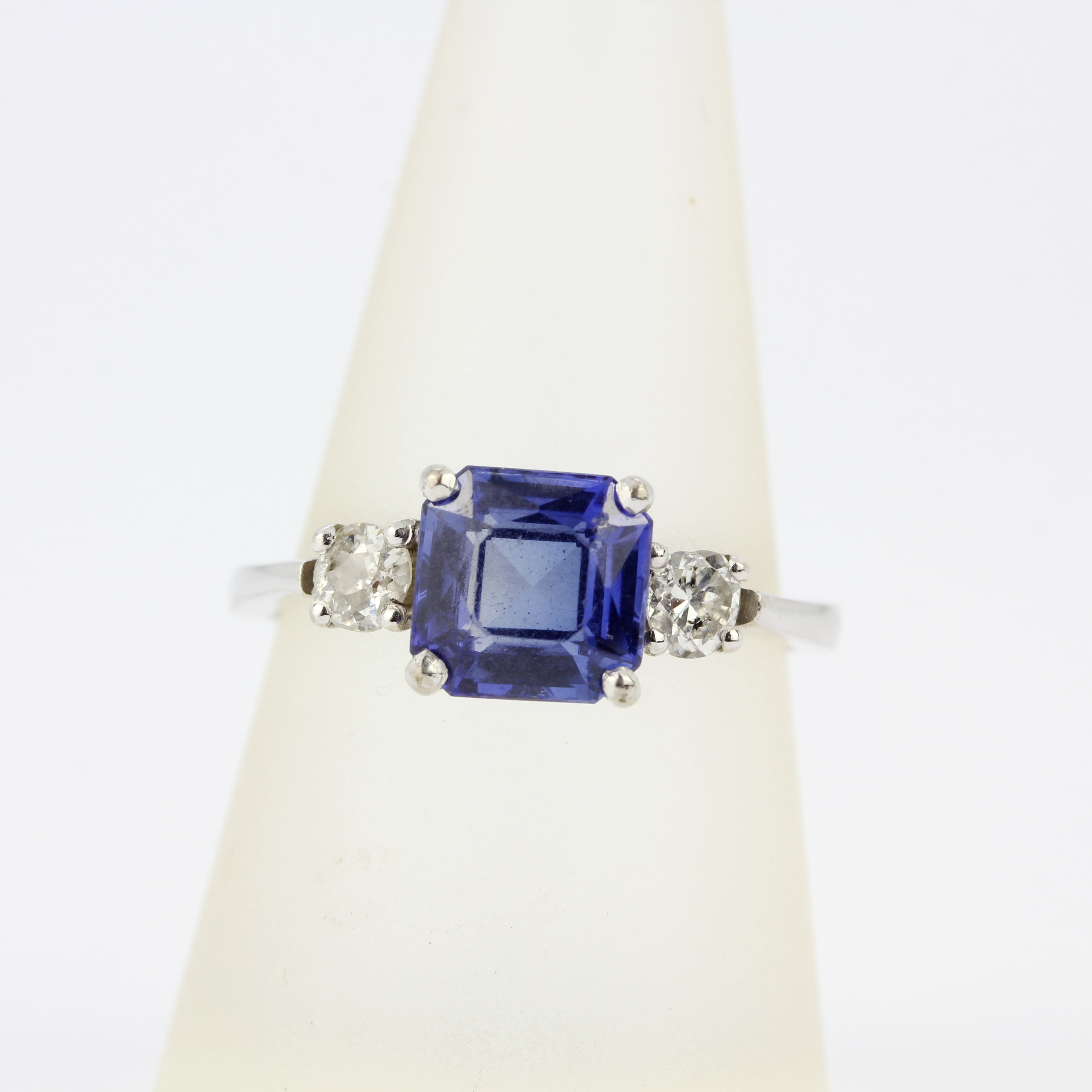 An 18ct white gold ring set with a fancy cut sapphire flanked by brilliant cut diamonds, diamonds