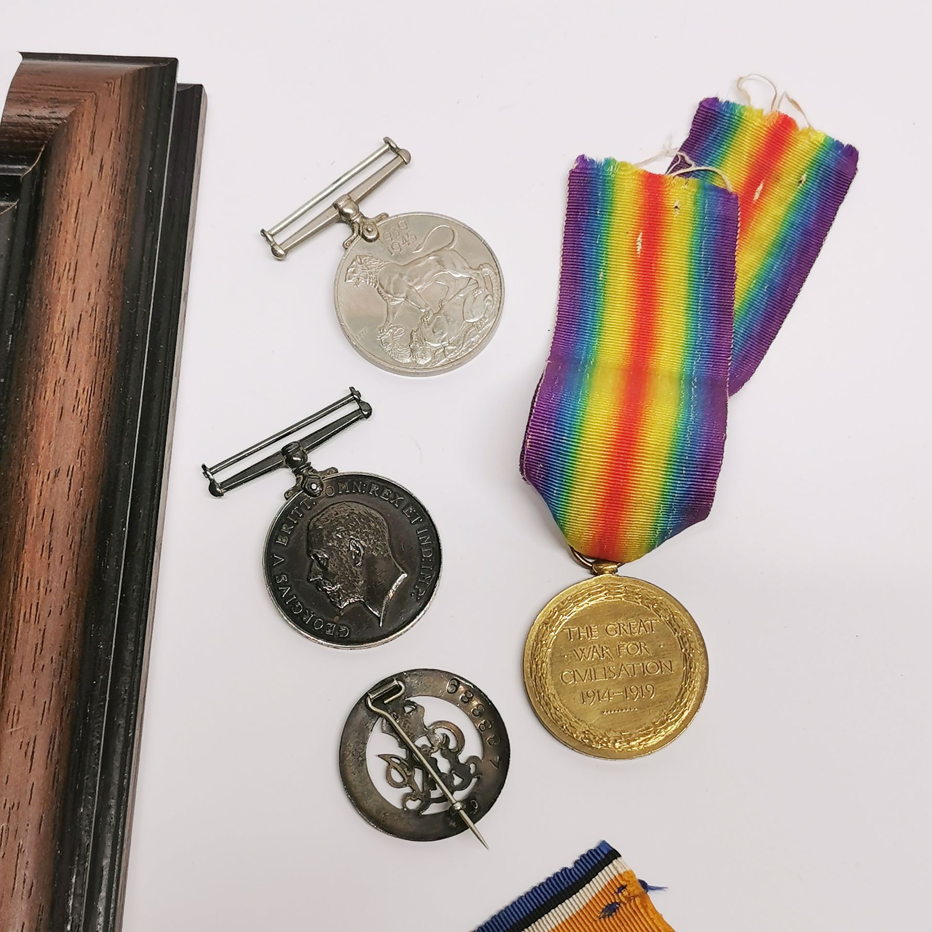 A frame containing two WWII medals with three others and a badge. - Image 3 of 4