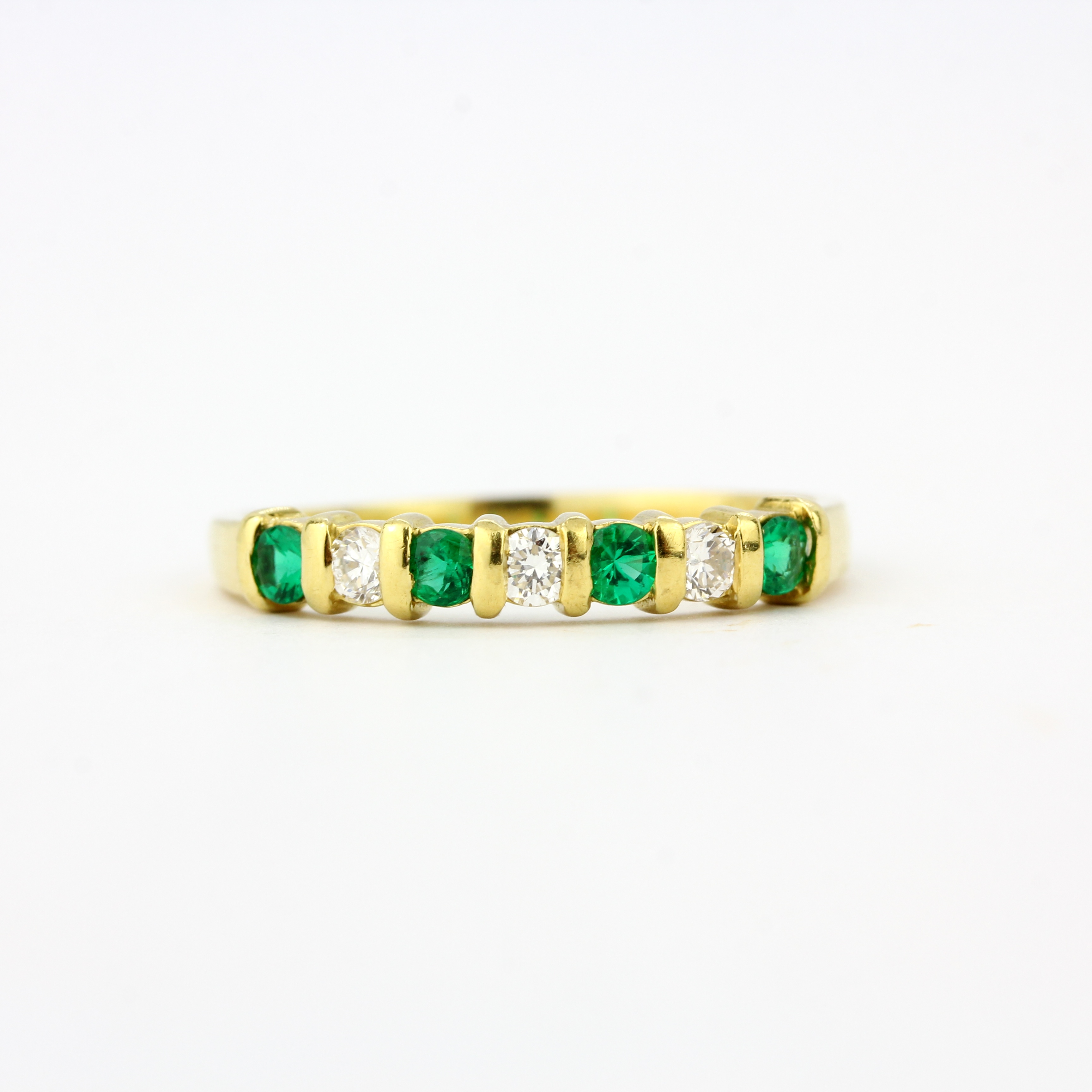 An 18ct yellow gold half eternity ring set with brilliant cut diamonds and emeralds, (O.5). - Image 2 of 3