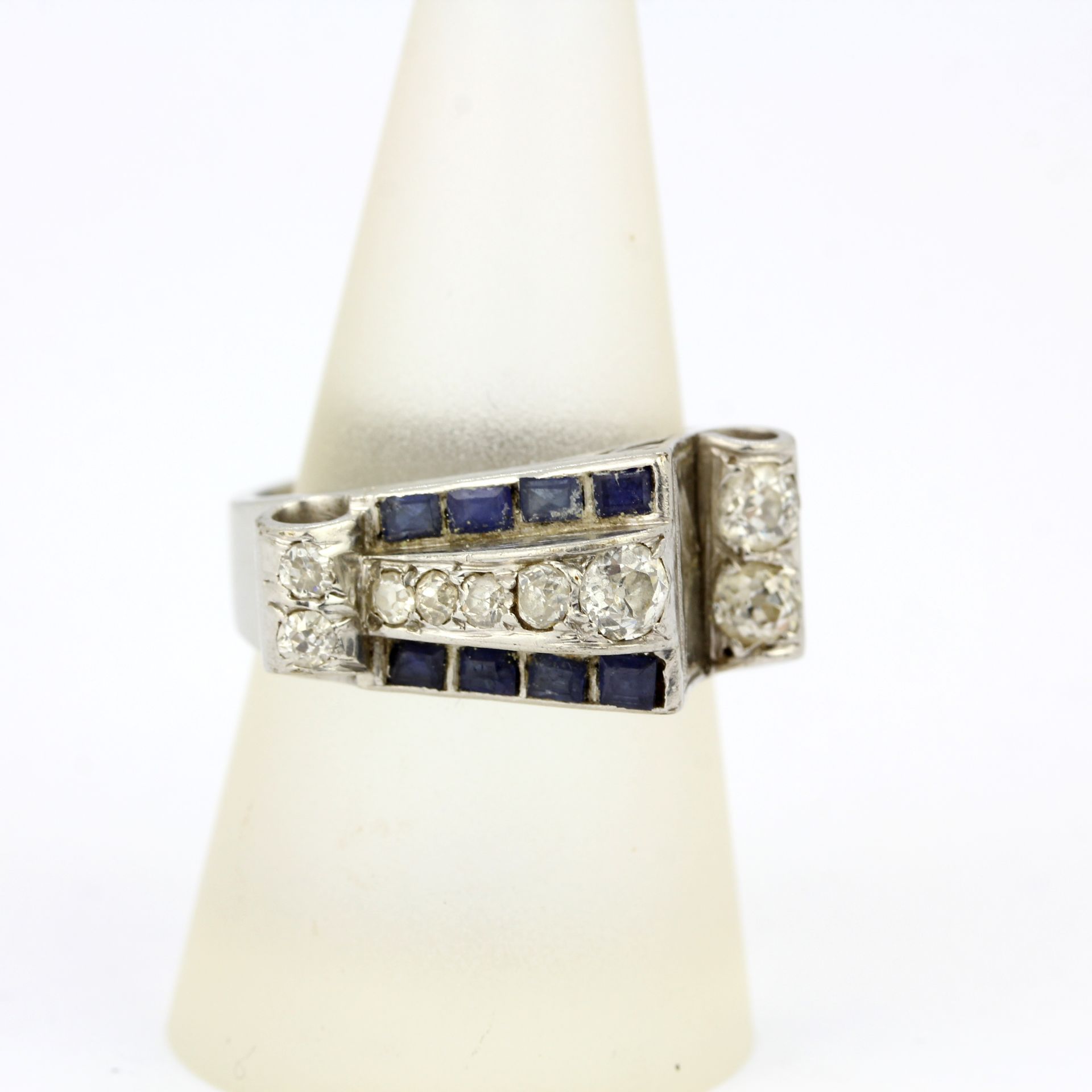 A white metal (tested minimum 9ct gold) ring set with step cut sapphires and old brilliant cut