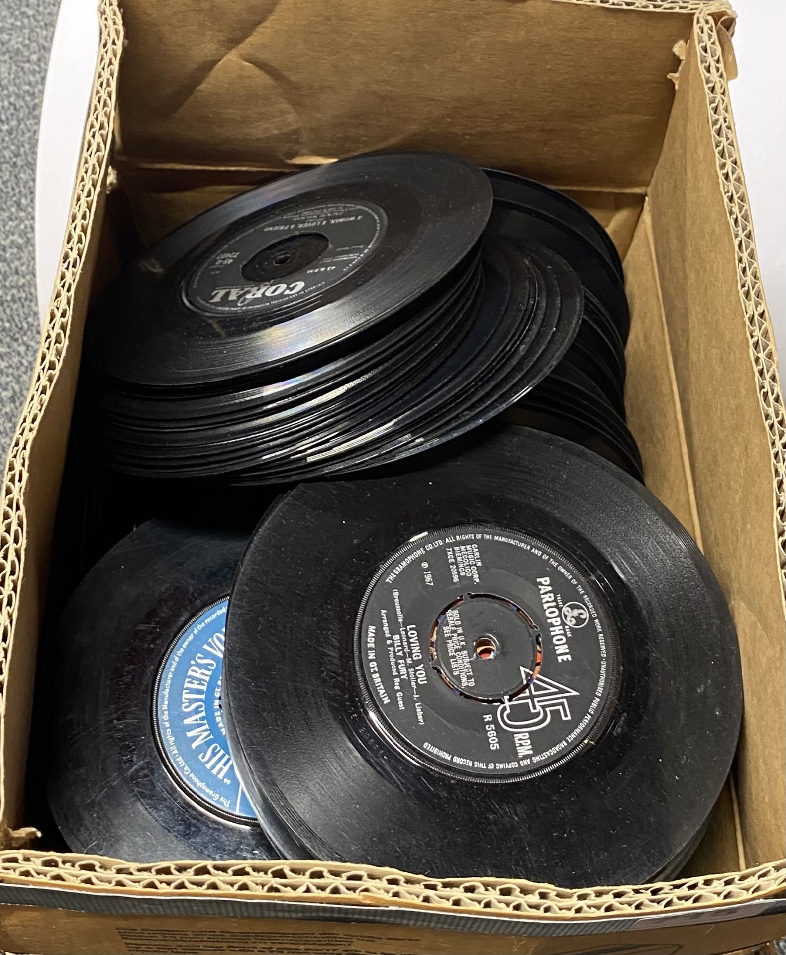 A box containing approx. three hundred 45-RPM single records from the 50's to the 80's.