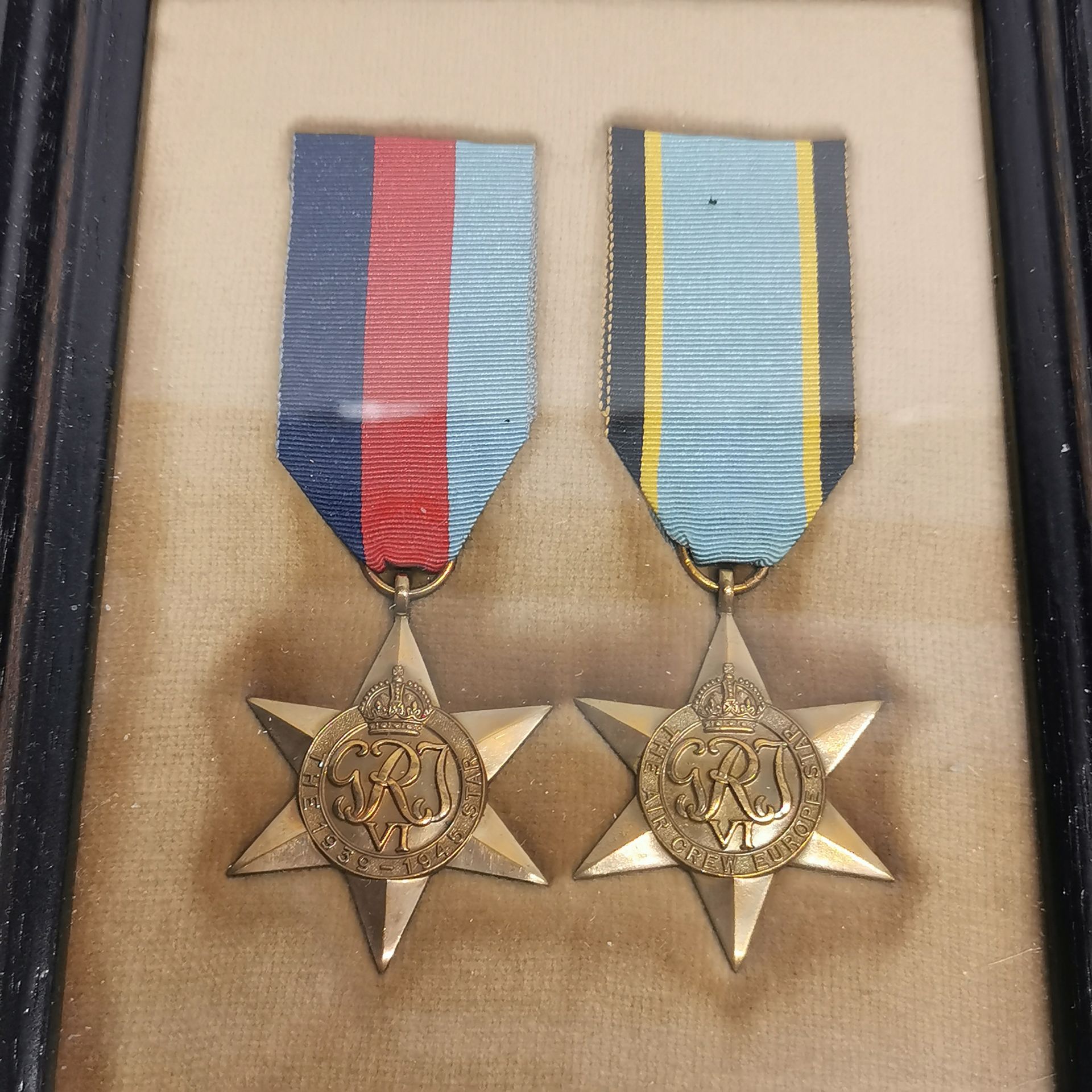 A frame containing two WWII medals with three others and a badge. - Image 4 of 4