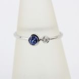An 18ct white gold ring set with a round cut sapphire and a brilliant cut diamond, ring size N.