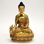 A Tibetan gilt bronze figure of a seated Buddha with temple quality hand painted face, H. 30cm.