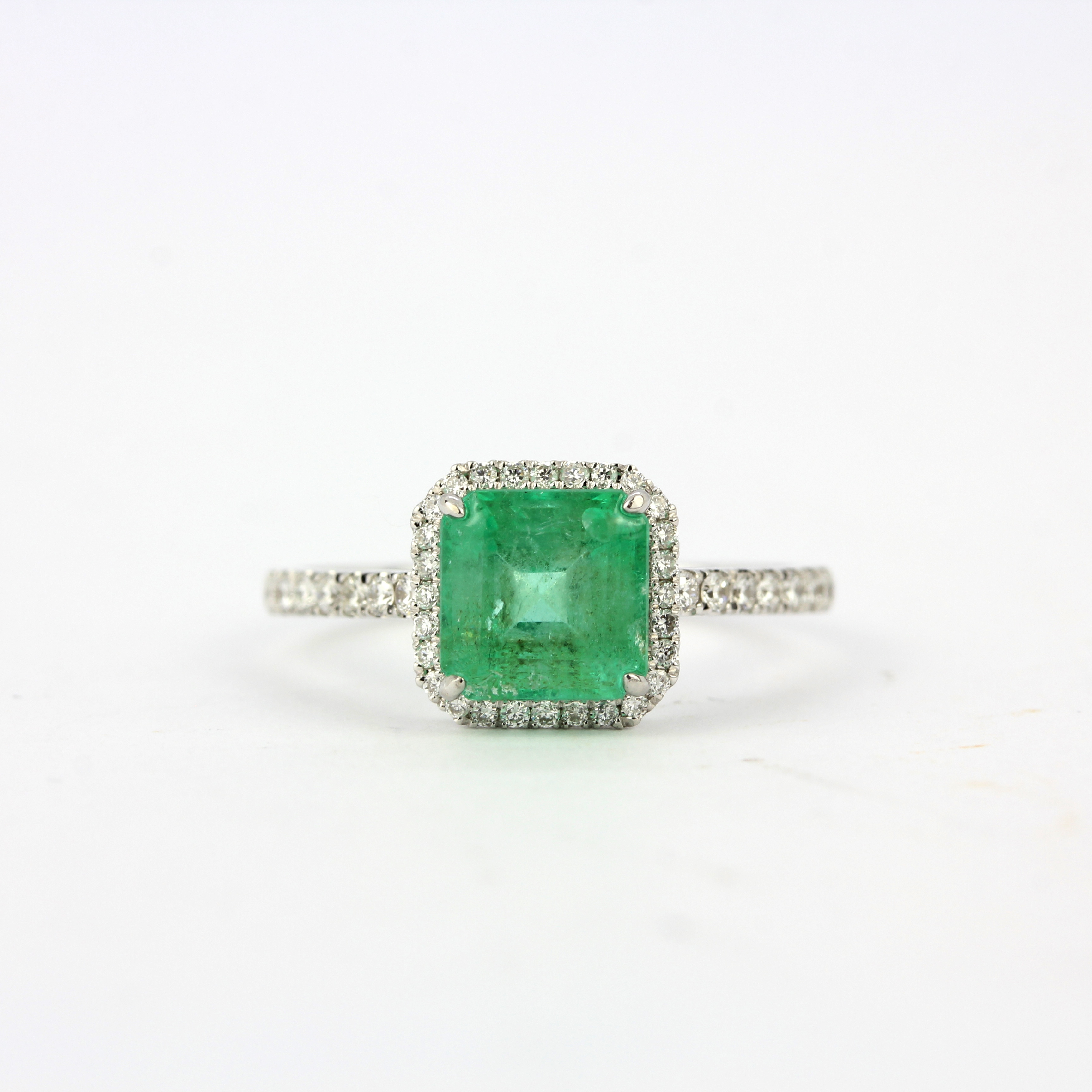 An 18ct white gold ring set with an emerald cut emerald and diamonds, ring size P.
