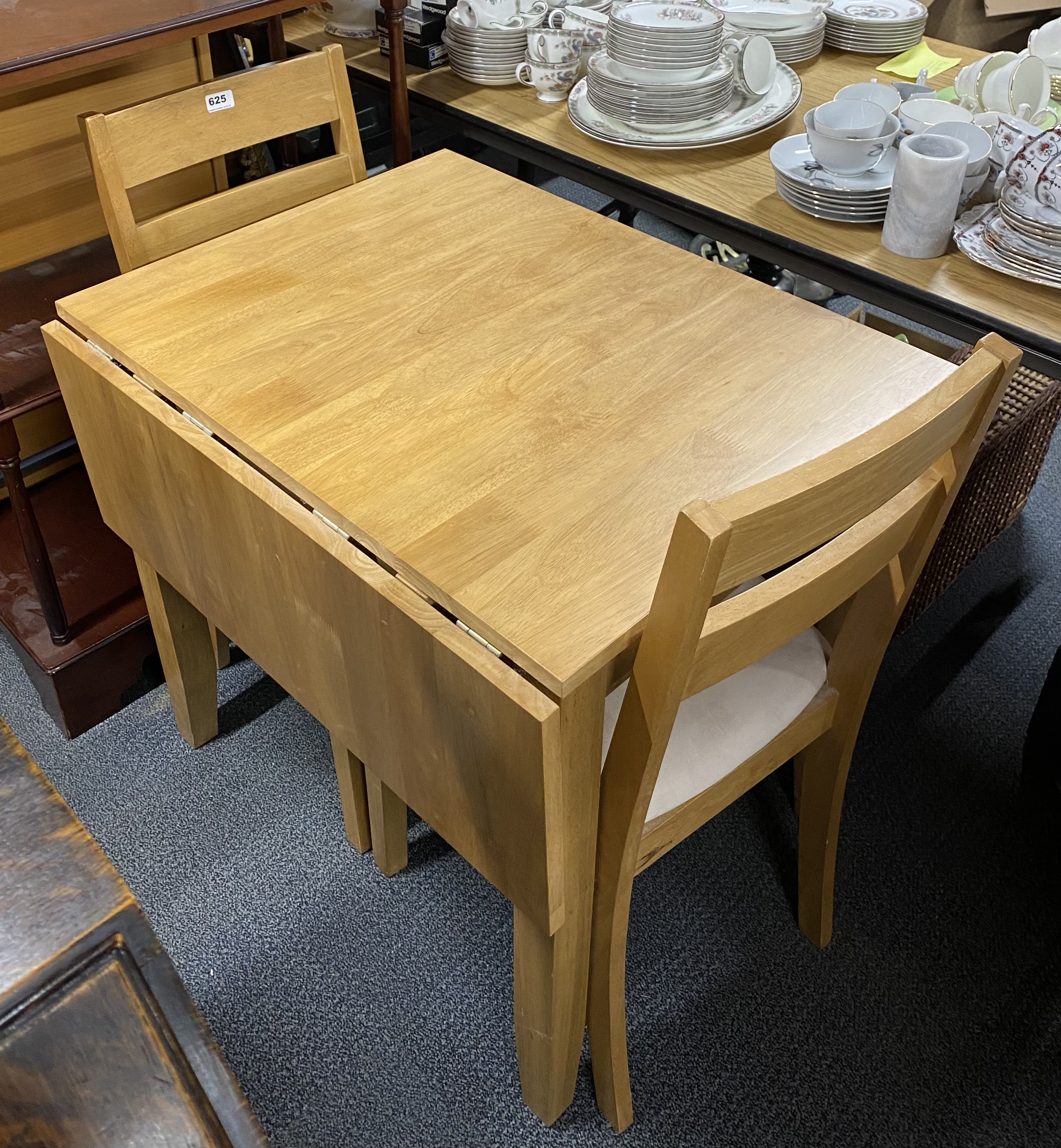 A contemporary drop leaf beechwood kitchen table and two chairs.
