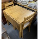 A contemporary drop leaf beechwood kitchen table and two chairs.