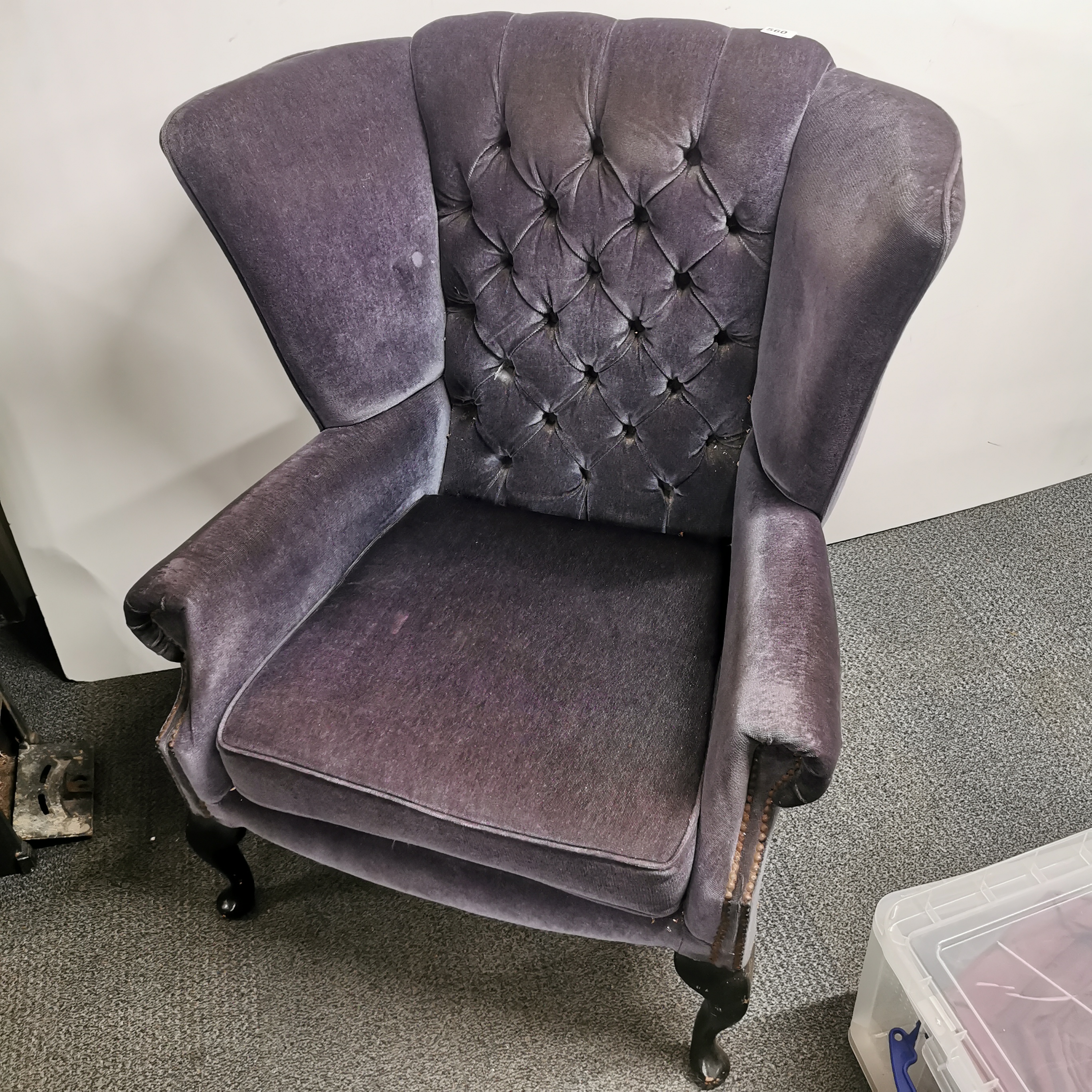 A plum velvet upholstered wing backed armchair.