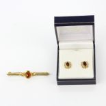 A pair of 9ct gold garnet set earrings and a yellow metal brooch.