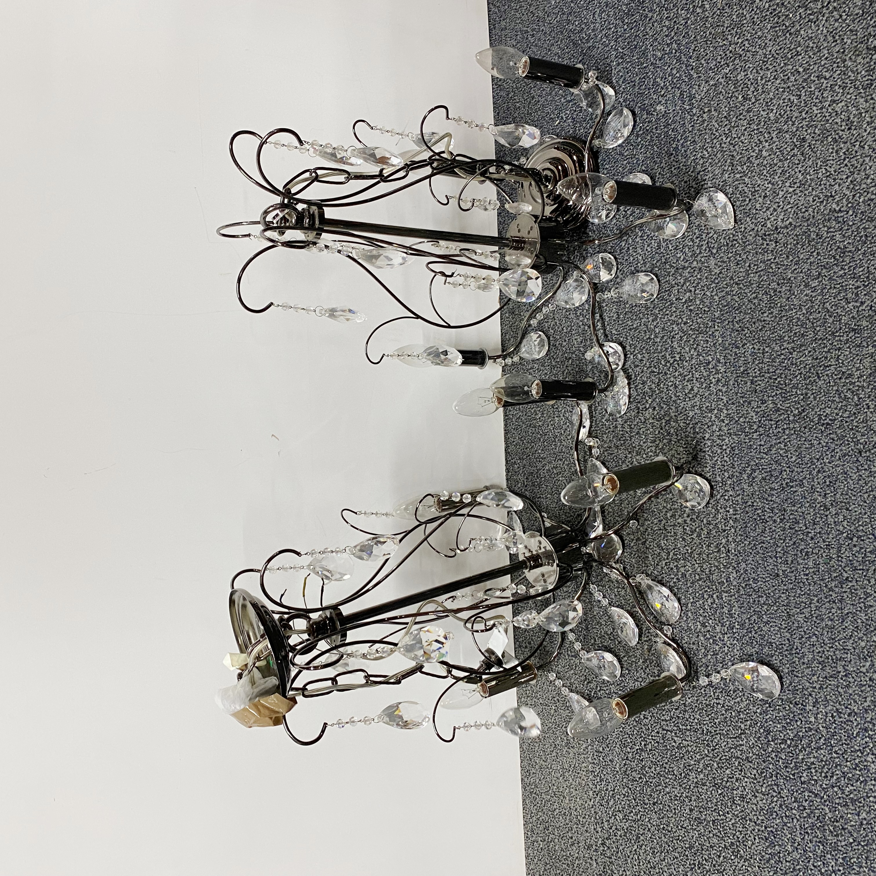 A pair of crystal and anodized chrome five branch chandelier candle light fittings, H. 49cm.