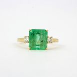 An 18ct yellow gold ring set with an emerald cut emerald flanked by diamonds, emerald 3.26ct,