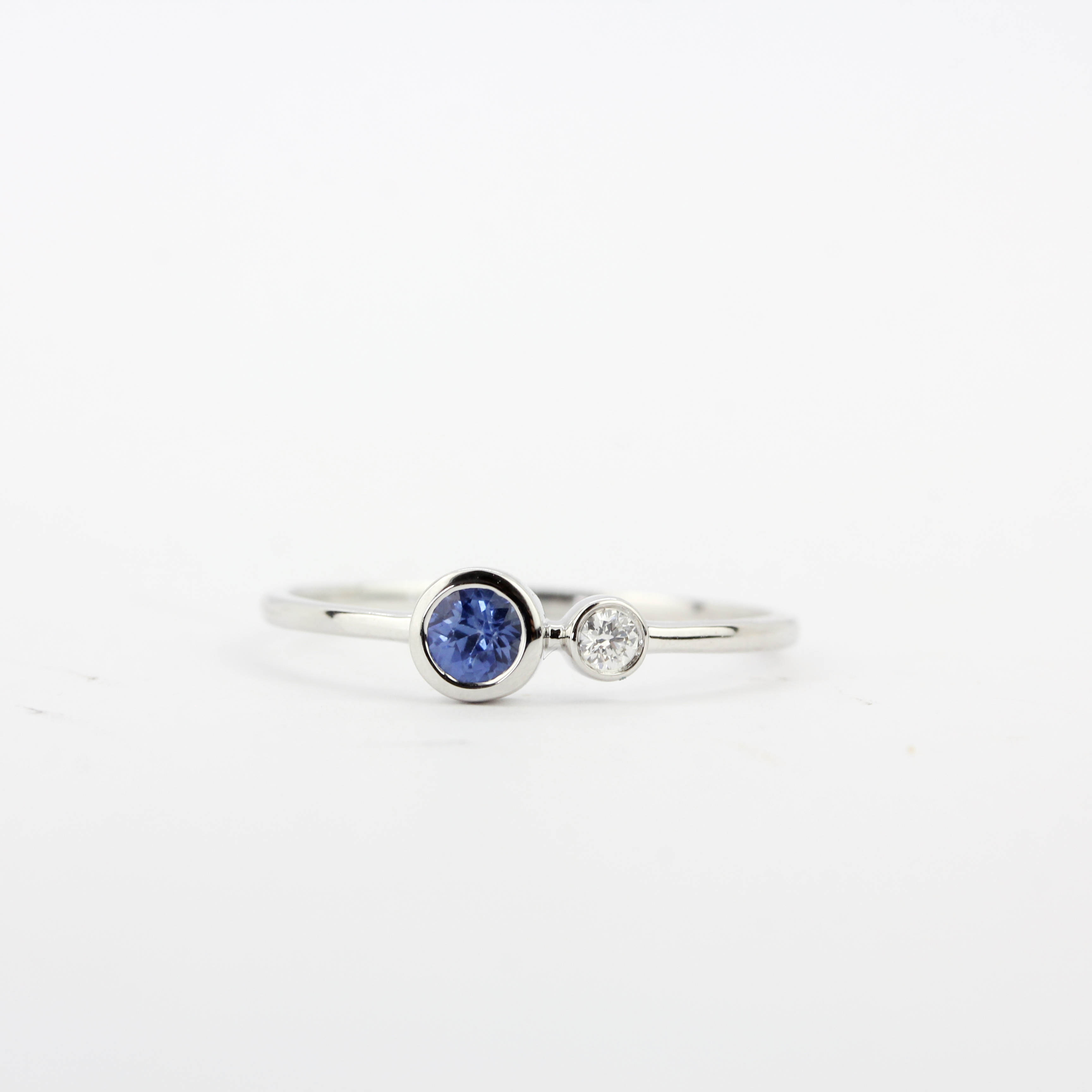 An 18ct white gold ring set with a round cut sapphire and a brilliant cut diamond, ring size N. - Image 2 of 3