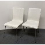 A pair of white leather upholstered and chrome chairs.