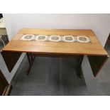 A 1970's tile topped teak drop leaf extending dining table, overall 255 x 87cm.