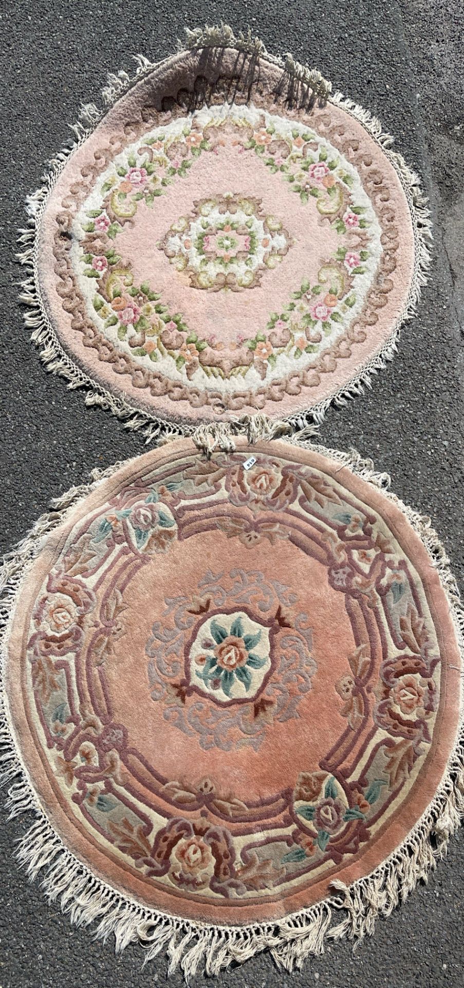 A pink ground washed wool Chinese rug together with a similar wool rug, largest dia. 125cm.