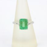 An 18ct white gold ring set with an emerald cut emerald and trillion cut diamonds, emerald 2.91ct,