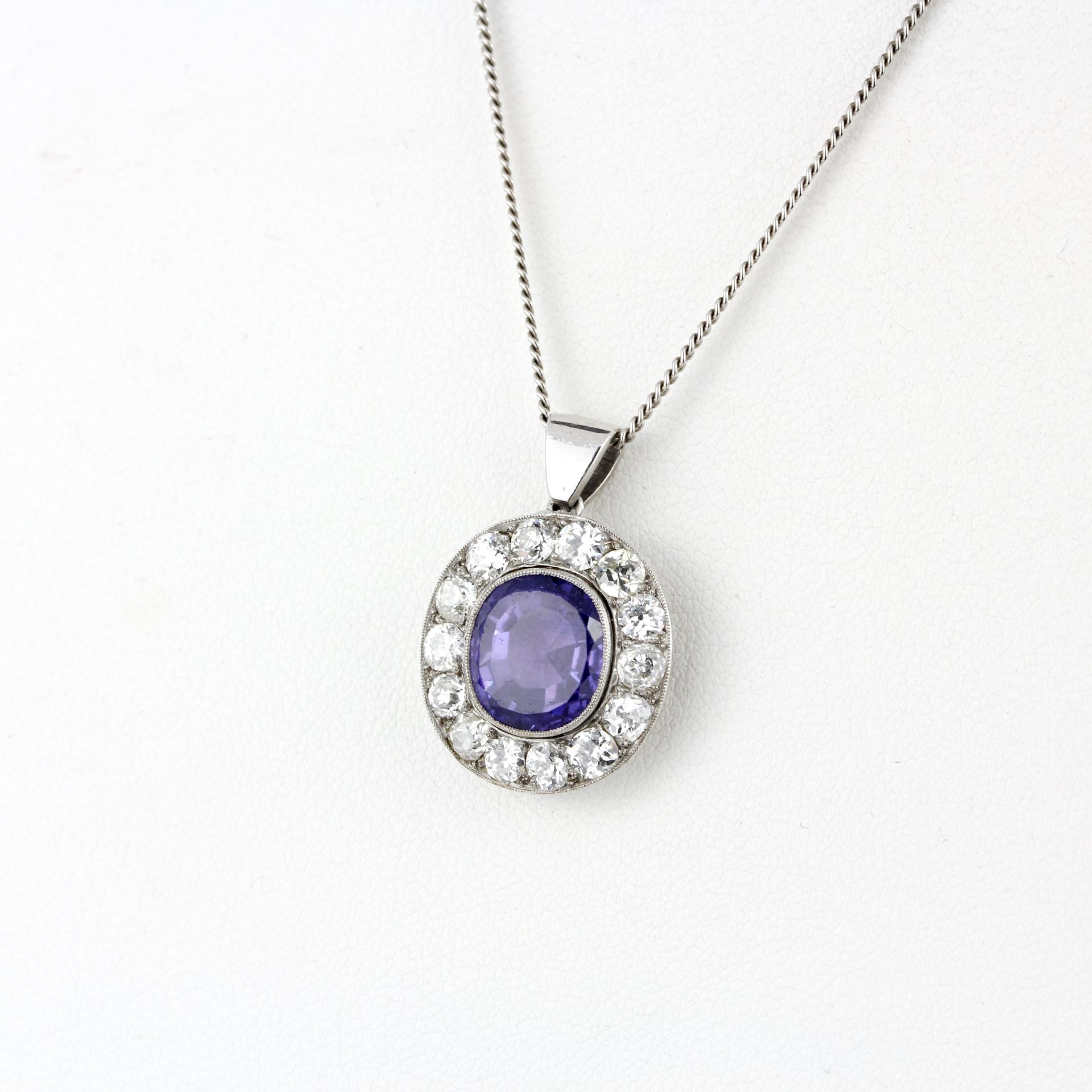A white metal (tested minimum 9ct gold) pendant set with an oval cut purplish sapphire surrounded by - Image 2 of 4