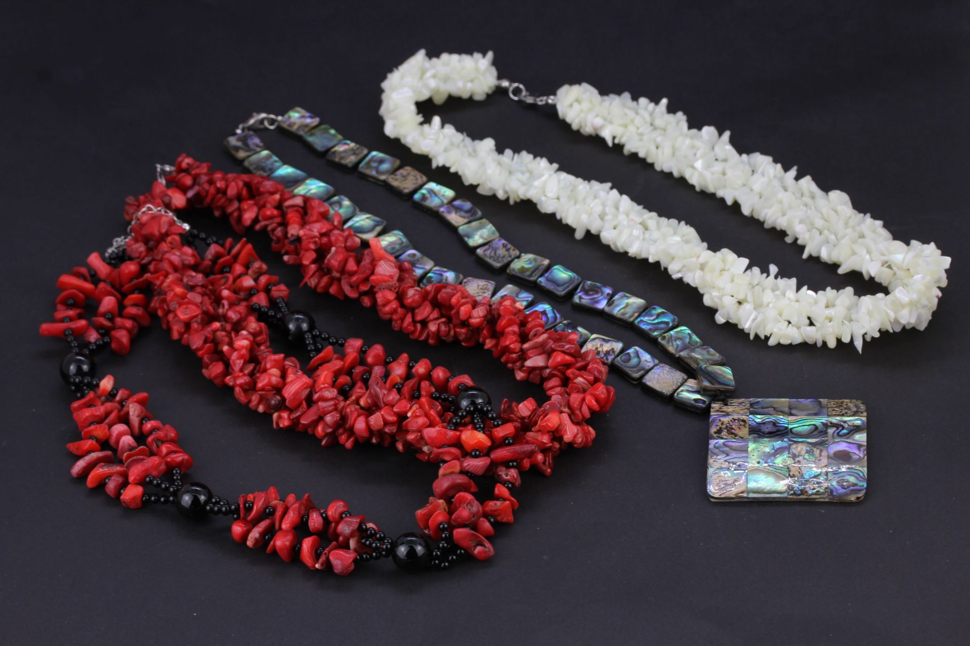 Two coral necklaces and two mother of pearl necklaces.
