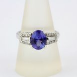 A 18ct white gold ring set with an oval cut tanzanite and tapered baguette and brilliant cut