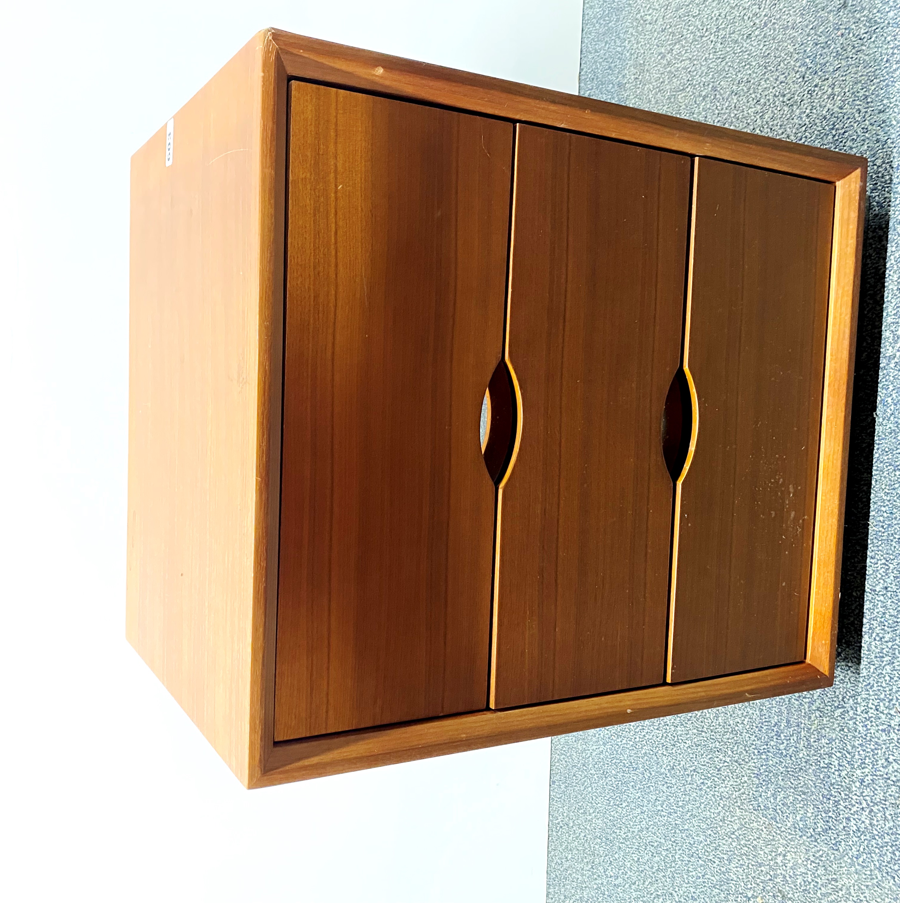 A contemporary teak finished three drawer chest, 50 x 40 x 62cm, with a chrome plinth.