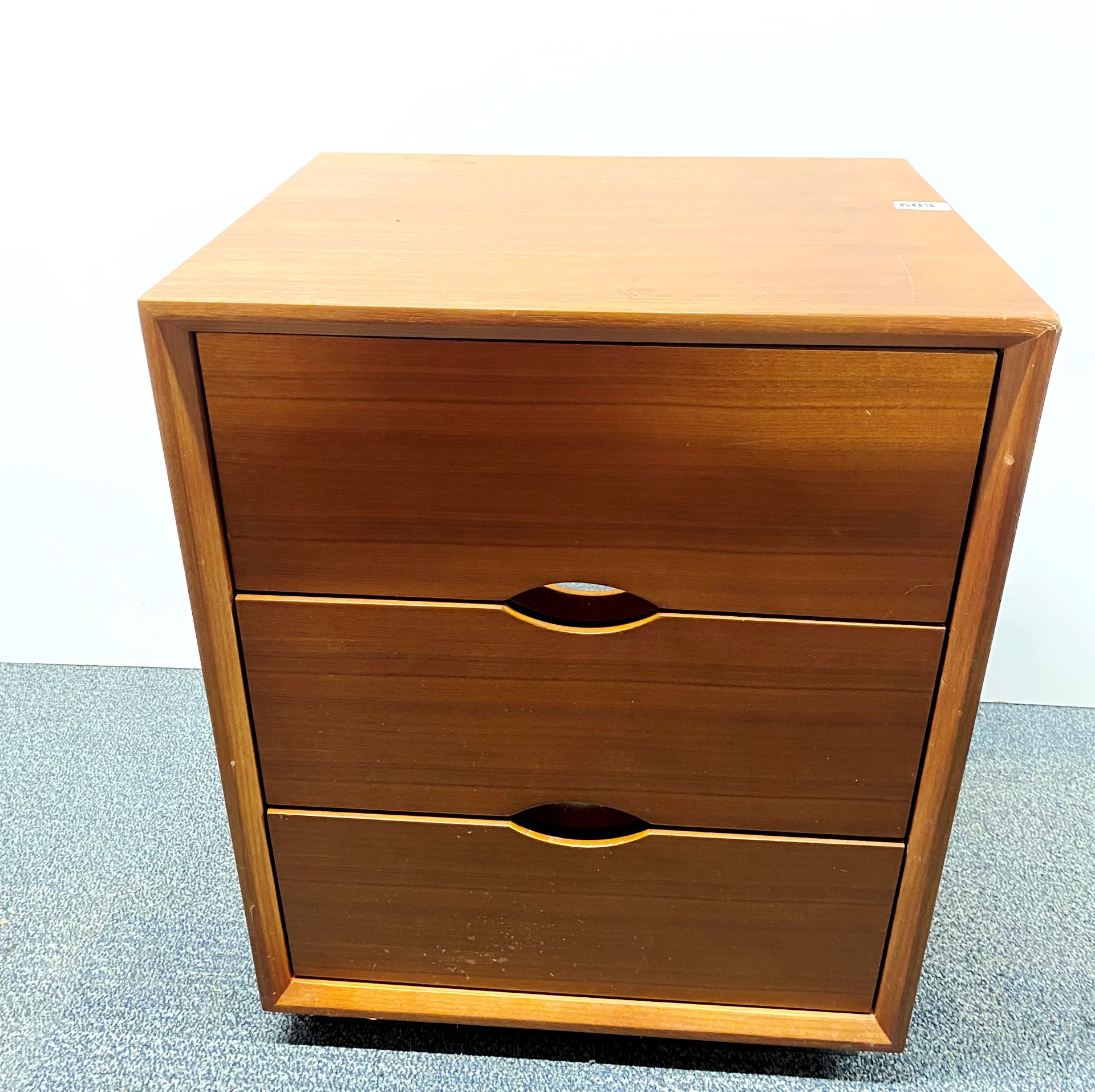 A contemporary teak finished three drawer chest, 50 x 40 x 62cm, with a chrome plinth.