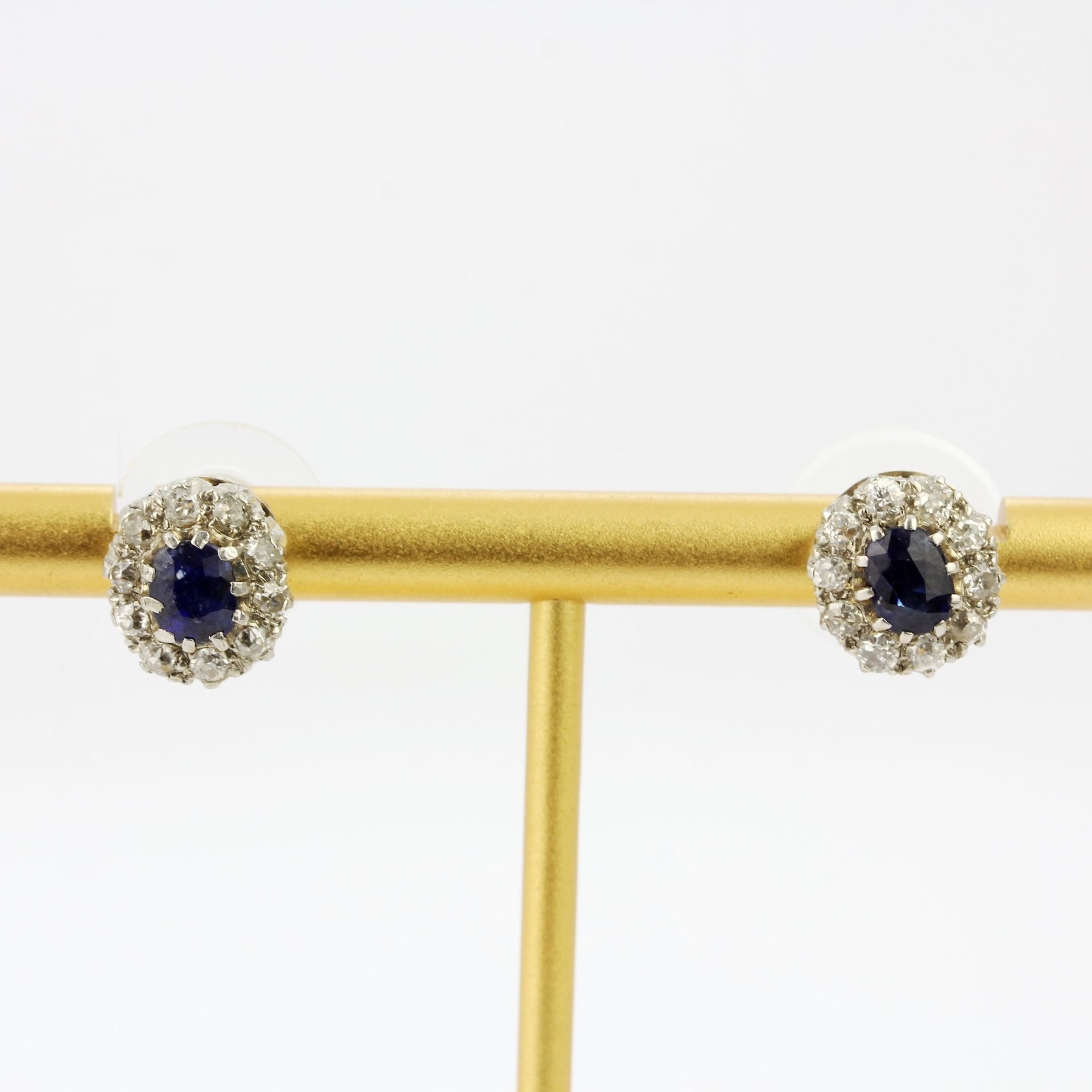 A pair of white metal (tested gold) diamond and sapphire cluster earrings, Dia. 1cm. With rubber