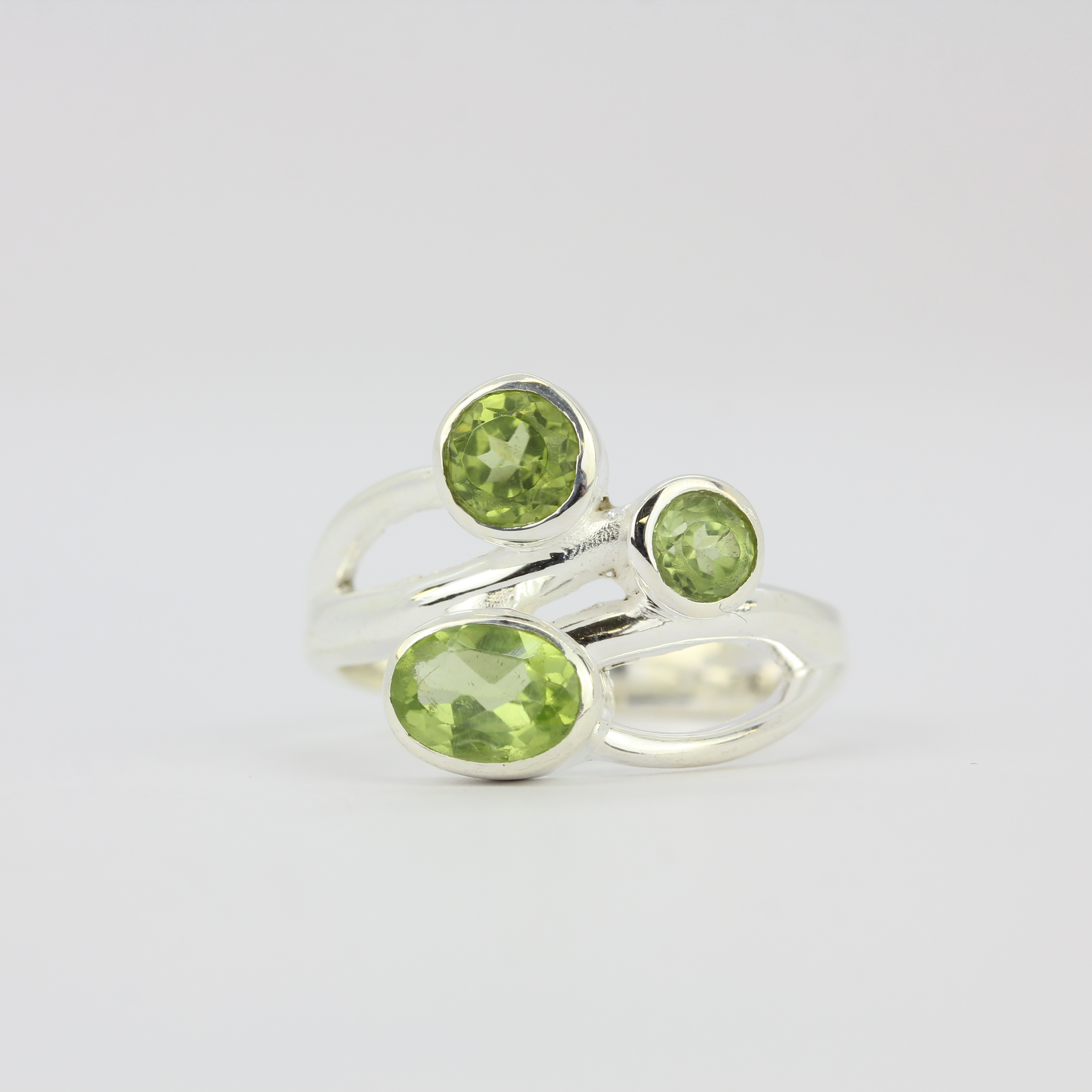 A 925 silver ring set with oval and round cut peridots.