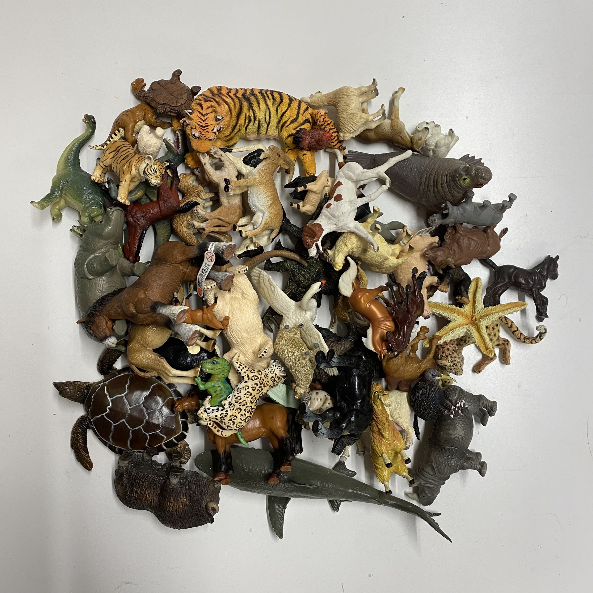 A box containing various animals and dinosaurs including Schleich and others.