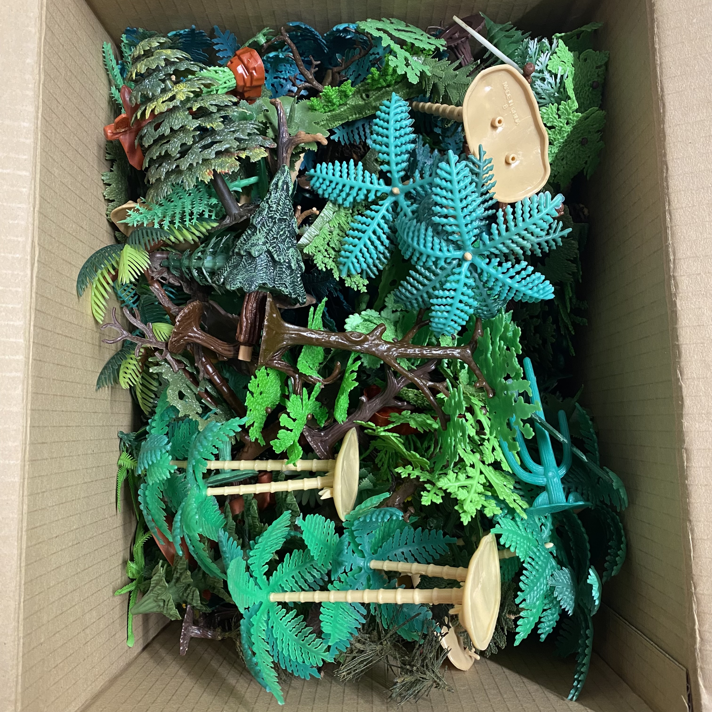 A box containing plastic trees etc. possibly for a diorama.