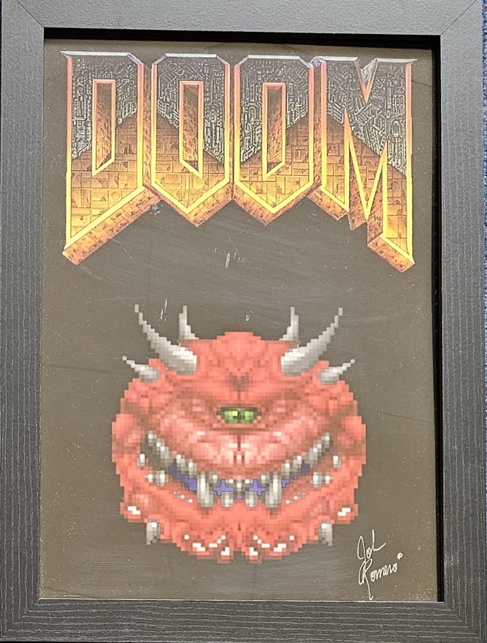 John Romero signed Doom illustrated piece. Framed to approx. size 18x14inch. Good condition. All