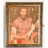 Chuck Berry framed colour photo; Chuck Berry plays his guitar in purple wester style shirt.