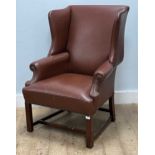 A modern tan leather wing back armchair