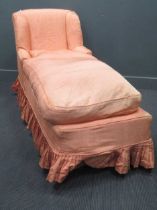 A day bed upholstered in a salmon pink satin material and a stool upholstered In the same material