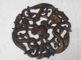 An oriental circular stone disc decorated in fretwork with three linked dragons, 17.5cm diameter