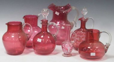 A collection of Victorian cranberry glass mainly jugs and decanters, but also some white glass