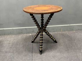 A late 19th century table, the round tooled top set on an ebonised and gilded bobbin turned