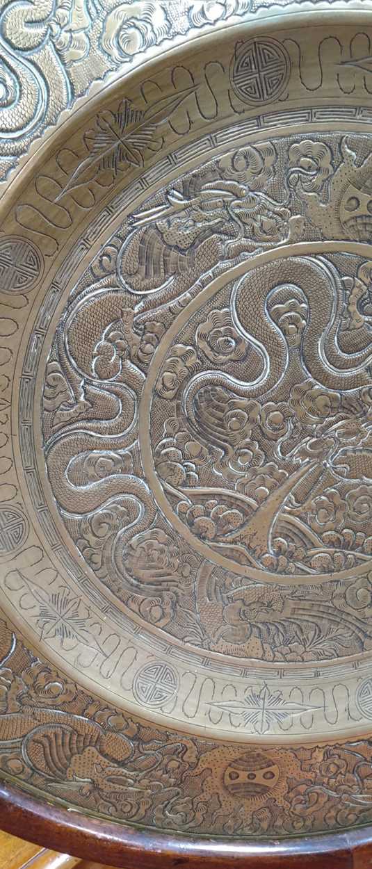 A Chinese circular brass dish on carved wood stand, early 20th century, decorated in relief with - Image 3 of 10
