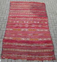 A red ground tribal runner decorated with geometric stripes 165 x 150cm